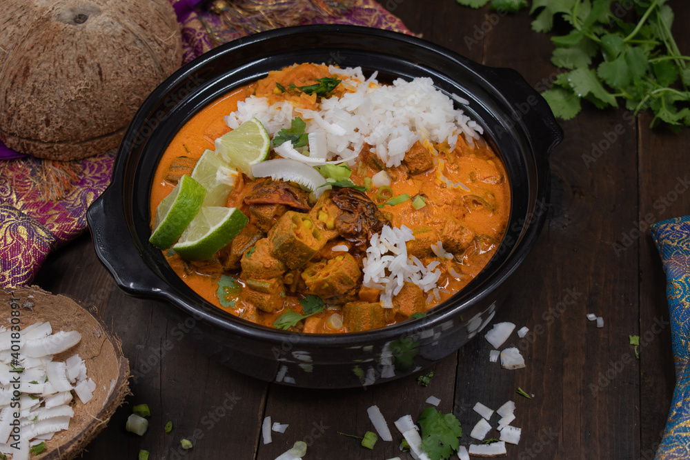 Vegan thai red curry with okra and peppers over jasmine rice, in black clay bowl Vegan thai red curry with okra and peppers over jasmine rice, in black clay bowl