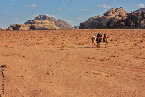 Bedouins ride a camel towards the mountains in the Wadi rum desert