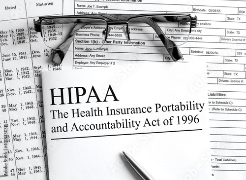 Paper with text HIPAA on a financial table with eyeglasses and metal pen