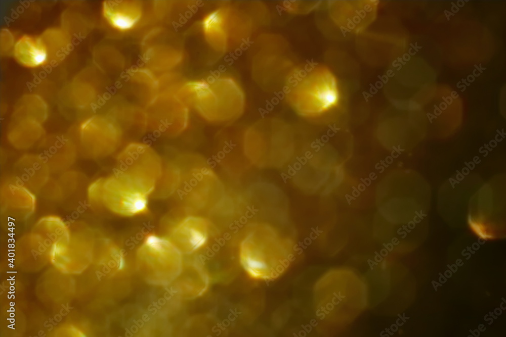 Obraz premium Golden bokeh background with soft light and circular reflections. Warm abstract texture ideal for festive themes, celebration, luxury, or elegant design elements