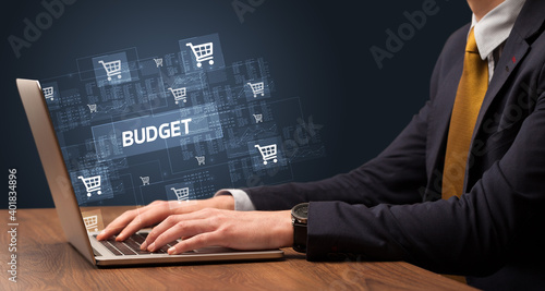 Businessman working on laptop with BUDGET inscription, online shopping concept