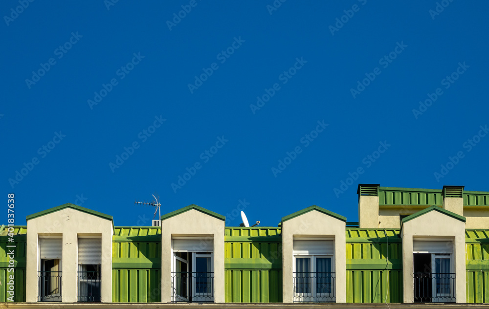 Green painted dormers against a deep blue sky