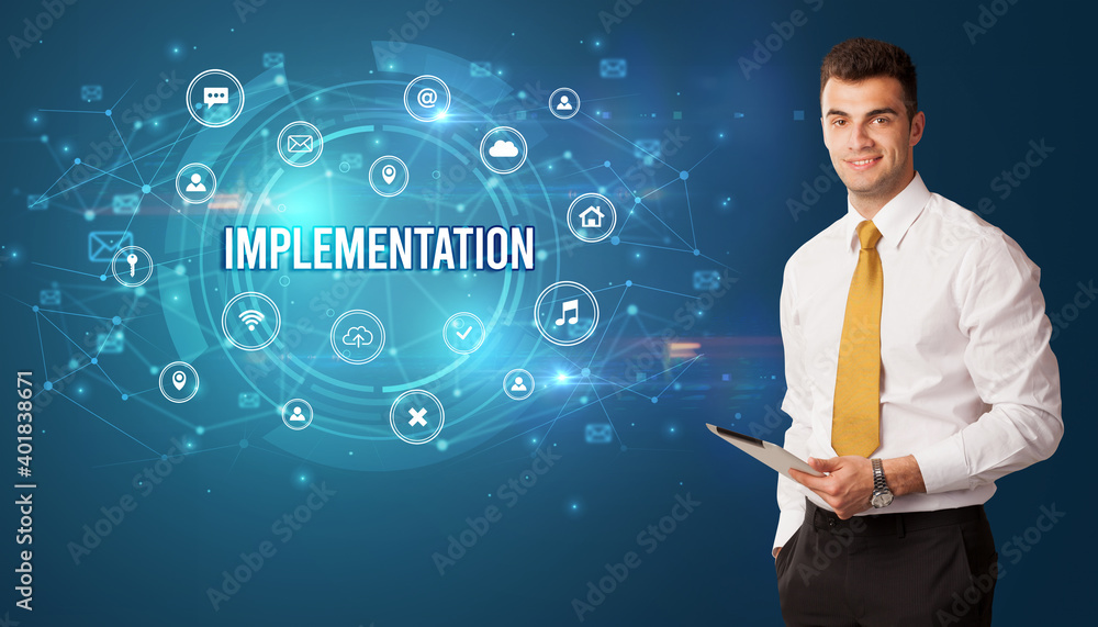 Businessman thinking in front of technology related icons and IMPLEMENTATION inscription, modern technology concept Businessman thinking in front of technology related icons and IMPLEMENTATION inscription, modern technology concept