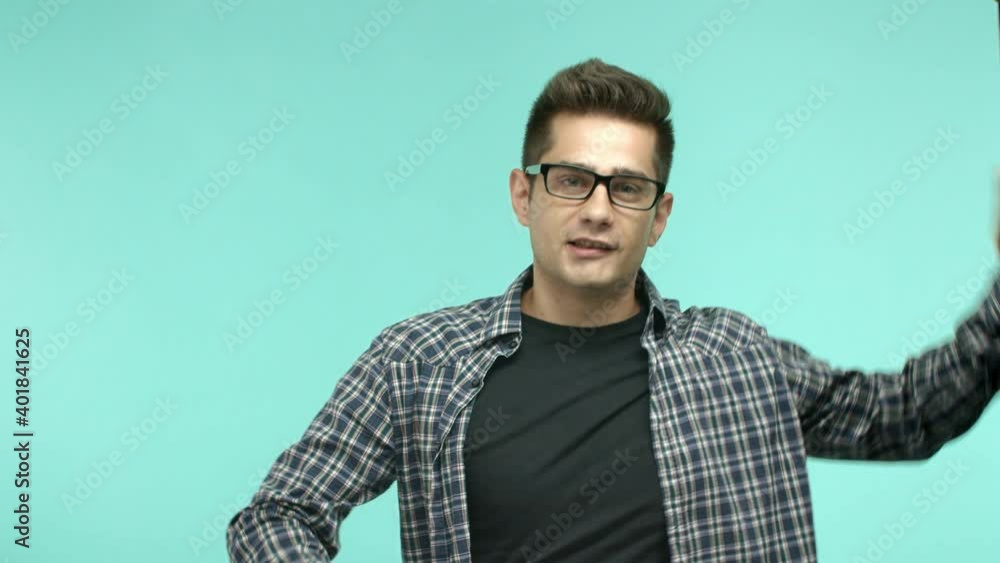 Cheerful young man in glasses dancing, showing peace disco gesture and smiling, having fun, standing over mint background Cheerful young man in glasses dancing, showing peace disco gesture and smiling, having fun, standing over mint background