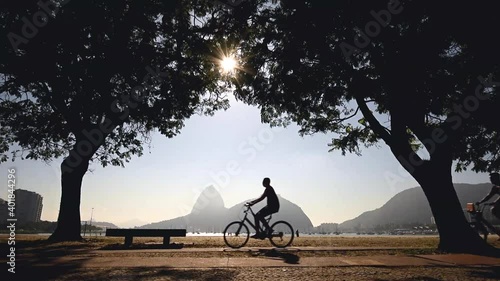 People Cycling Under Trees in Front of the Botafogo Beach in the Morning With Sugarloaf Mountain in the Horizon, Rio de Janeiro, Brazil photo