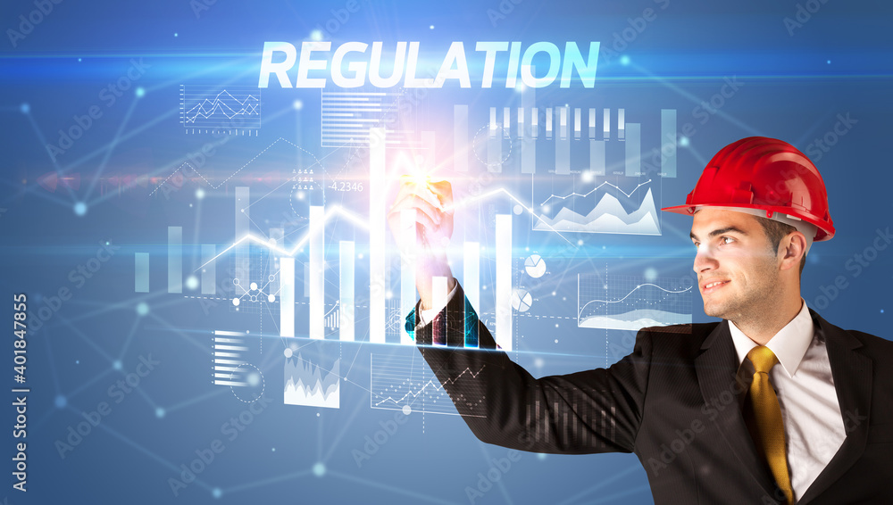 Handsome businessman with helmet drawing REGULATION inscription, architecture business plan concept Handsome businessman with helmet drawing REGULATION inscription, architecture business plan concept