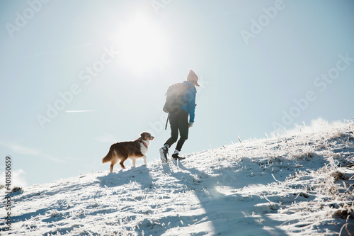 Wandernde Frau mit Hund im Schnee am Bergkamm photo
