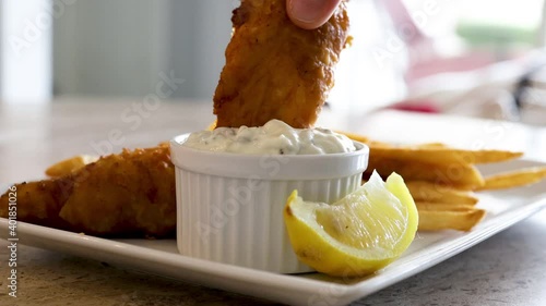 Dipping Fried Cod Into Tarter Sauce photo
