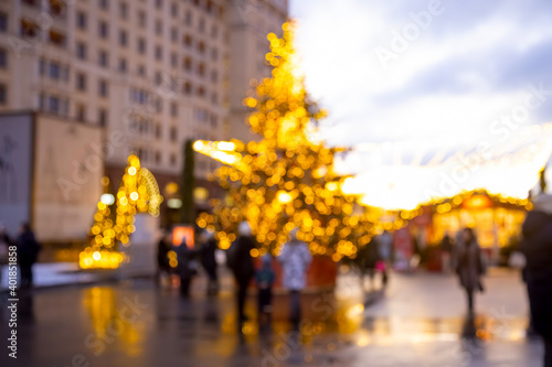 Fototapeta Naklejka Na Ścianę i Meble -  Christmas holiday background. Christmas tree in shining garland at New Year's outdoor marketplace fair in blur. place for copysace