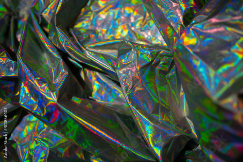 Iridescent fabric holographic background. Crumpled surface shiny metallic foil