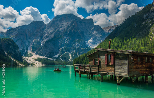 alpine lake with green water and boat and wooden hut Lago di Braies