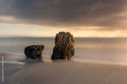 sunset on the beach with two rocks and long exposure photo