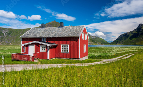 red house on green meadows with blue sky and white clouds in Norway