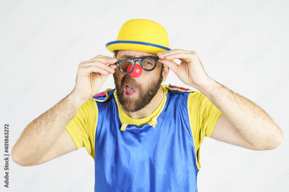 A clown in a bright blue and yellow suit adjusts his glasses A clown in a bright blue and yellow suit adjusts his glasses