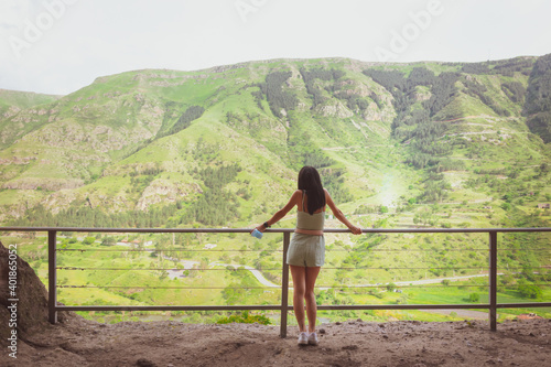 Wallpaper Mural Back view of Young slim woman standingin vardzia and looking away to greenery of georgian landscape. Torontodigital.ca
