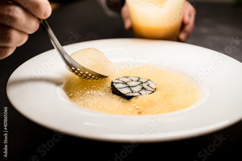 Fototapeta Naklejka Na Ścianę i Meble -  view on man's hand holding skimmer with molecular froth and adds it to plate
