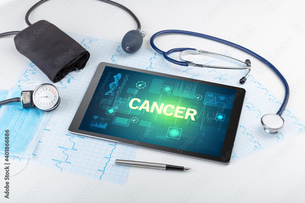 Tablet pc and medical stuff with CANCER inscription, prevention concept Tablet pc and medical stuff with CANCER inscription, prevention concept
