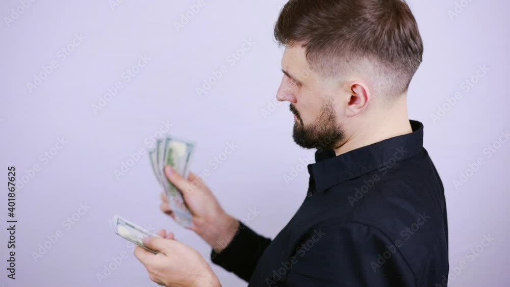 a male businessman stands sideways and counts dollar bills a male businessman stands sideways and counts dollar bills