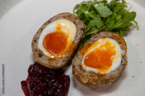 A delicious home made scotch egg on a white plate with salad