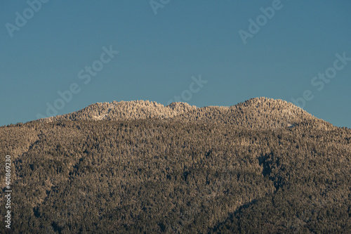 mountain peaks and slopes covered with a thin layer of snow under blue sky on a sunny morning 