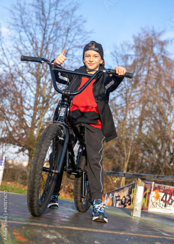 Junge mit schwarzen BMX-Fahrrad auf einem Sportplatz/Bahn. BMX-Räder sind das kleine Bike für große Sprünge. Beliebt als Sportgerät, mit dem künstliche Hindernisse und Kurven gemeistert werden. photo