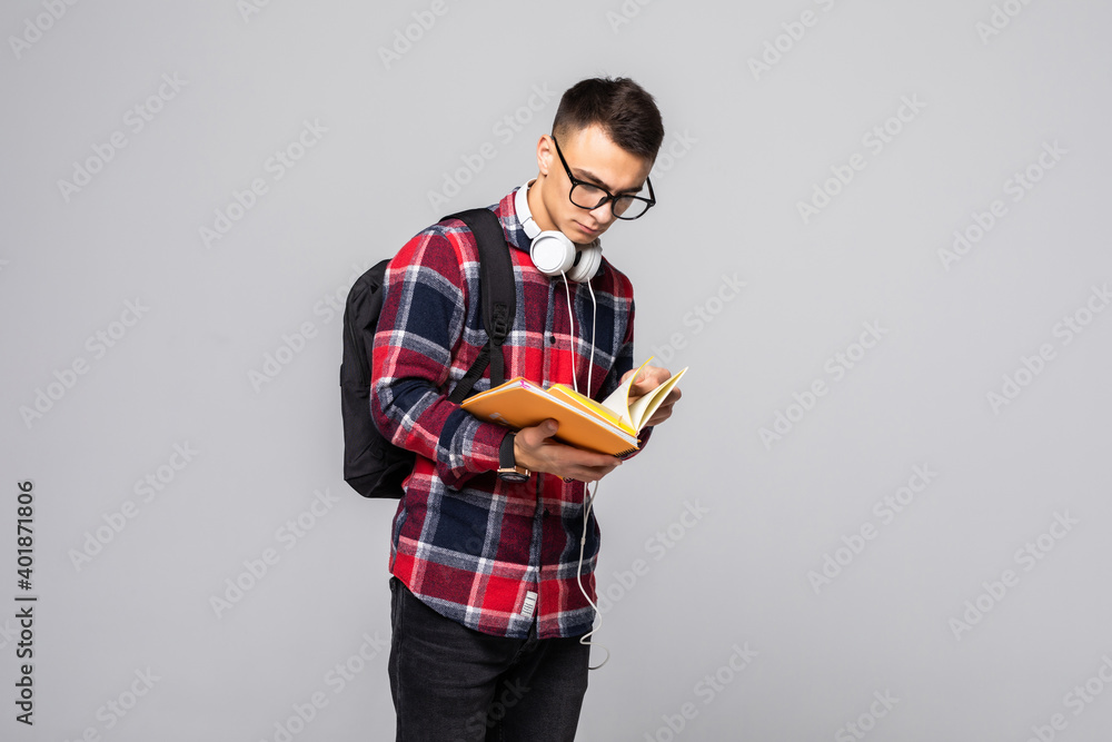 Handsome student with backpack and book smiling on gray background Handsome student with backpack and book smiling on gray background