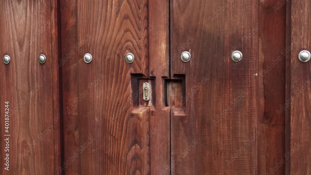 Heavy wood carved gate with rivets and a keyhole lock. Close-up. Heavy wood carved gate with rivets and a keyhole lock. Close-up.
