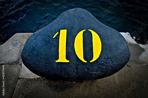 Number 10, ten, a yellow digit on a black harbor bollard. photo