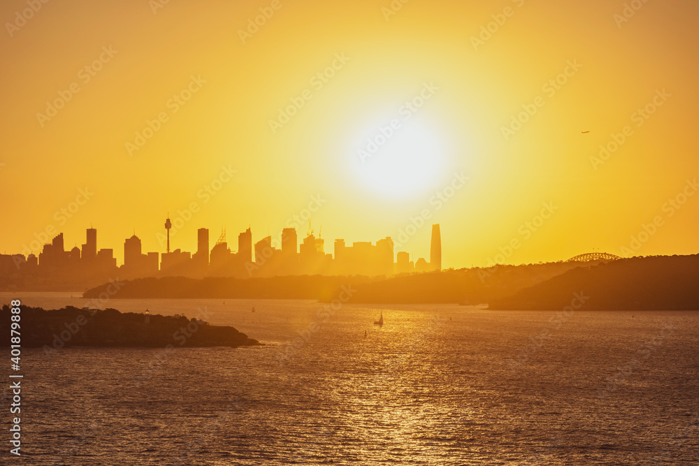 Beautiful evening sunset shot of the Sydney Harbour with the Sydney skyline in the background, seen from Fairfax Lookout at North Head Sanctuary. Shot in December 2020. Boats cruising in harbour.