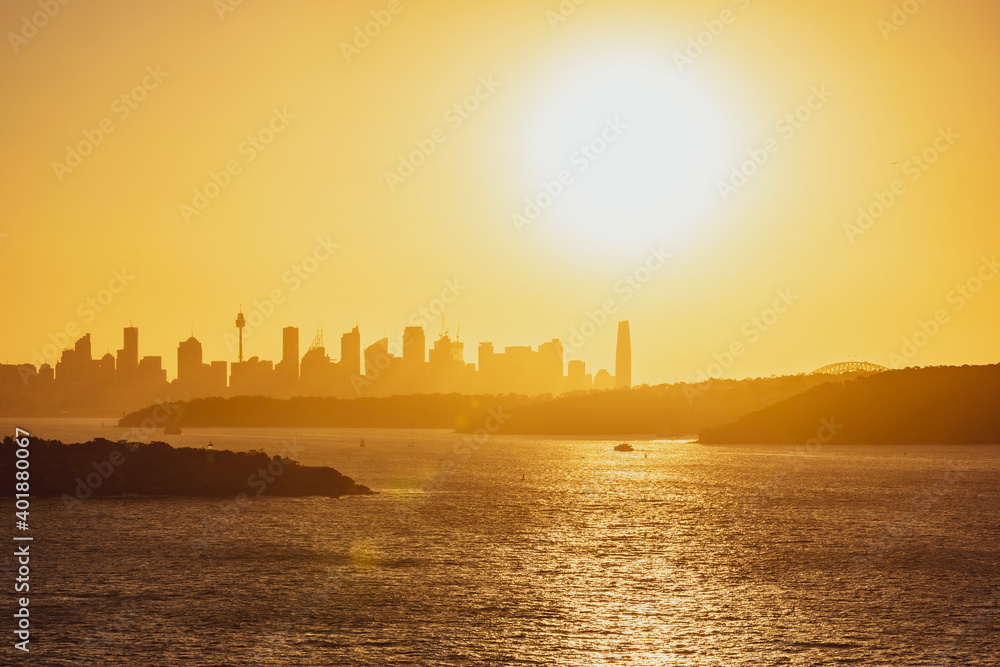 Beautiful evening sunset shot of the Sydney Harbour with the Sydney skyline in the background, seen from Fairfax Lookout at North Head Sanctuary. Shot in December 2020. Boats cruising in harbour.