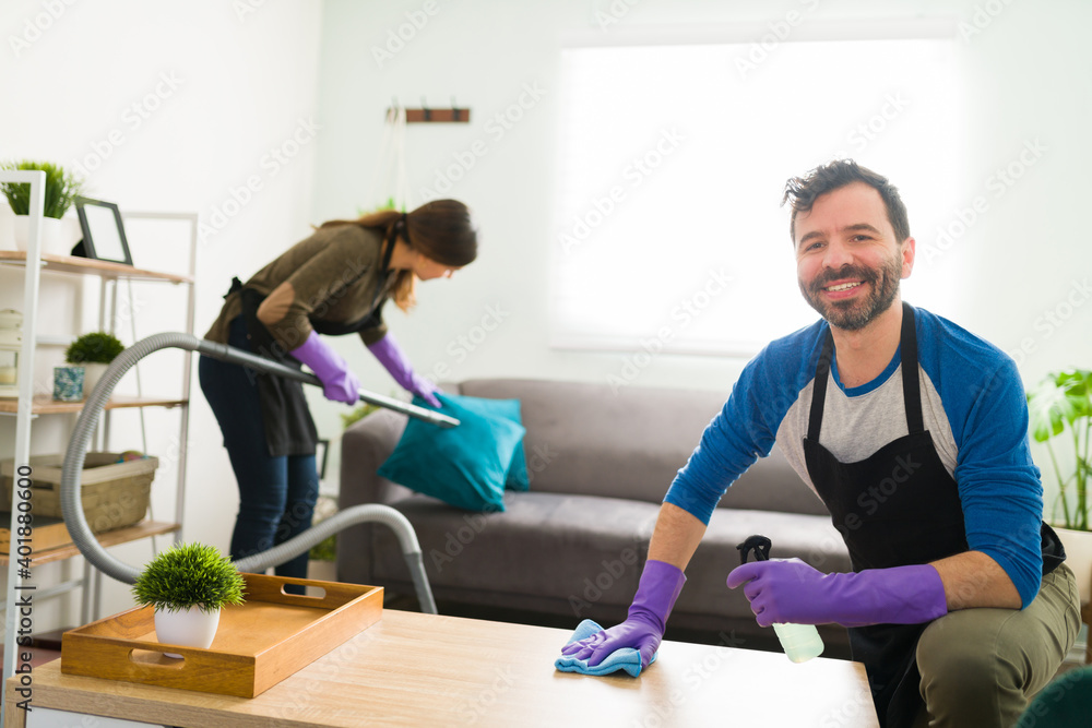 Obraz premium Happy man cleaning the house with his partner