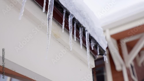 Huge thick icicles hanging from the roofs are melting under the spring sun