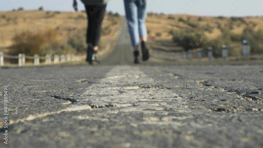 Clsoe up of feet on two women walks out of camera on country road Clsoe up of feet on two women walks out of camera on country road