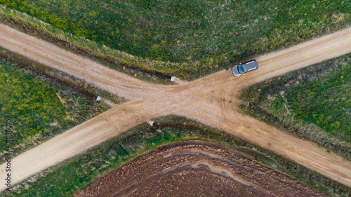 Canvas Print An aerial shot of a car at a crossroad in the middle of a field