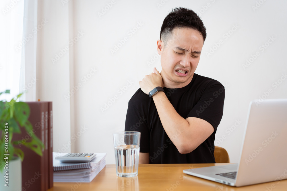 Asian young man in black t-shirt having a health problem from hard working or overworking. Asian young man in black t-shirt having a health problem from hard working or overworking.