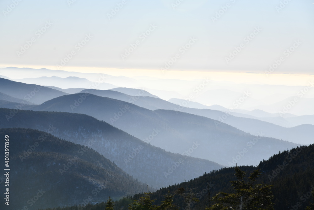 Spectacular view of mountain ranges silhouettes and fog in valleys during sunset time at Stowe, Vermont, USA