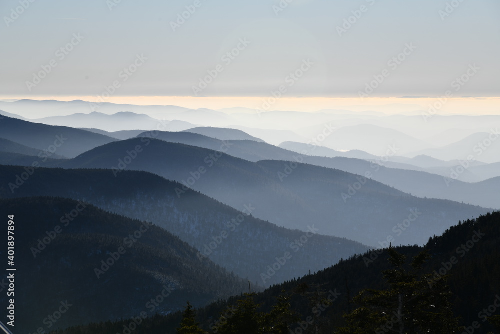 Spectacular view of mountain ranges silhouettes and fog in valleys during sunset time at Stowe, Vermont, USA