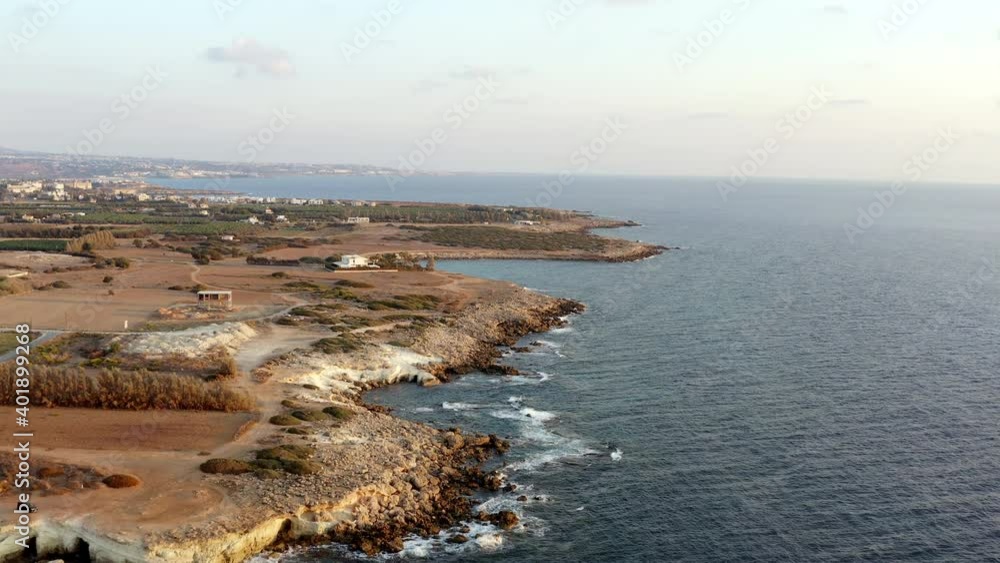 Drone video of the shores of the Mediterranean Sea waves which break the rocky shore on which stand houses and grow bushes with trees in a beautiful landscape. Aerial view nature cyprus. Drone video of the shores of the Mediterranean Sea waves which break the rocky shore on which stand houses and grow bushes with trees in a beautiful landscape. Aerial view nature cyprus.