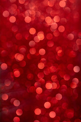 A vertical shot of a red blurred Christmas background with bokeh effect
