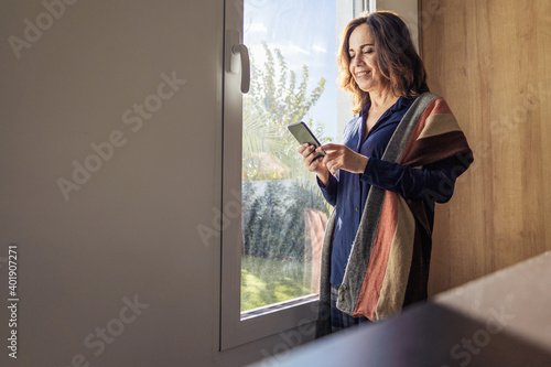 An attractive female standing in a room by a window