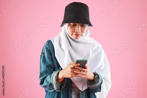 Fashion portrait of young beautiful asian muslim woman with wearing hijab isolated on pink background. © faishalabdula