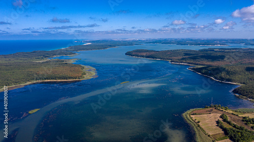 A panoramic shot from Durugol Turkey. There is a lake near a path filled with forest and green grass under the blue sky.