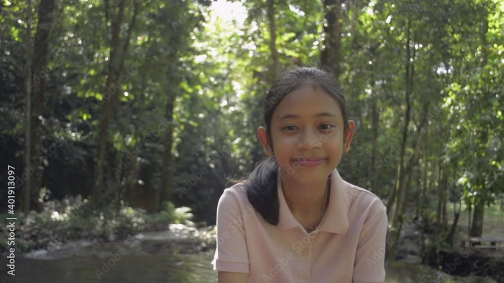 Portrait adorable girl in casual dress is smiling and looking at camera during camping trip at Sa Nang Manora Forest Park under morning sunlight in the summer time. Travel experience. Thailand. Portrait adorable girl in casual dress is smiling and looking at camera during camping trip at Sa Nang Manora Forest Park under morning sunlight in the summer time. Travel experience. Thailand.
