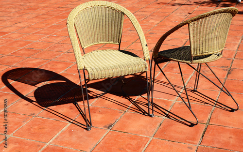Two wicker chairs with shadows in the sunlight