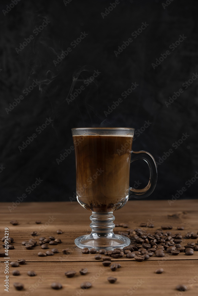 Steaming coffee over wooden surface and black background