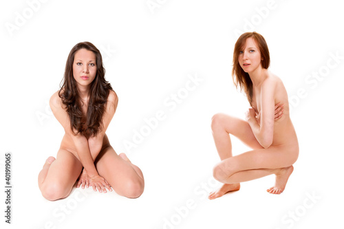 Two beautiful nude women covering themselves with their legs and arms, their private parts are not visible, isolated in front of white studio background