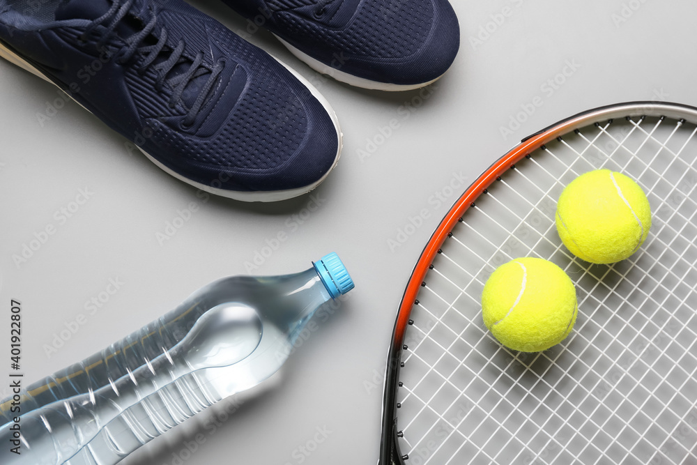 Sportive shoes, tennis racket and balls on light background
