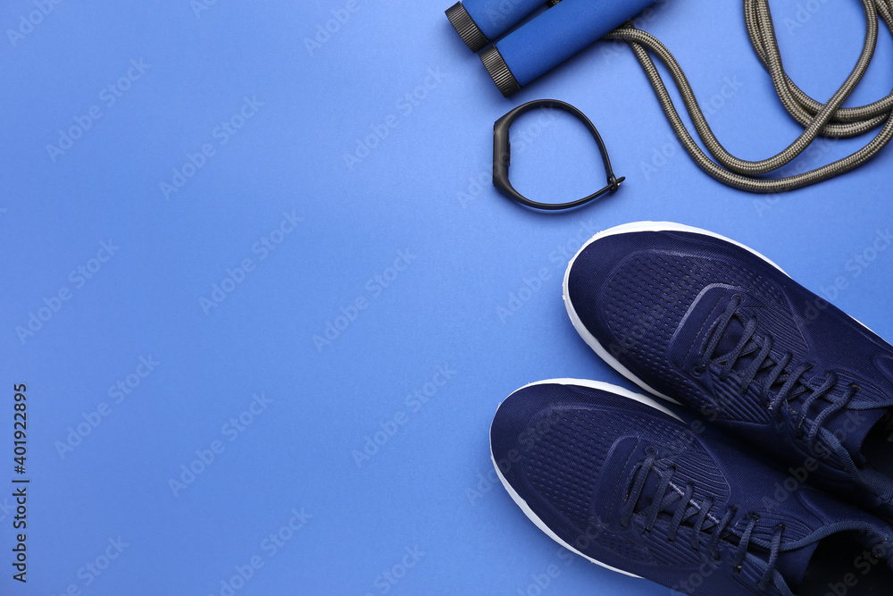 Fototapeta premium Sportive shoes and jumping rope on color background