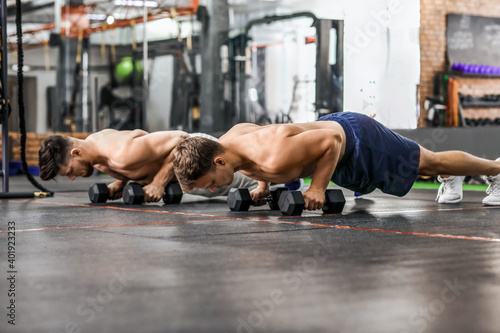 Handsome muscular men exercising with dumbbells in gym