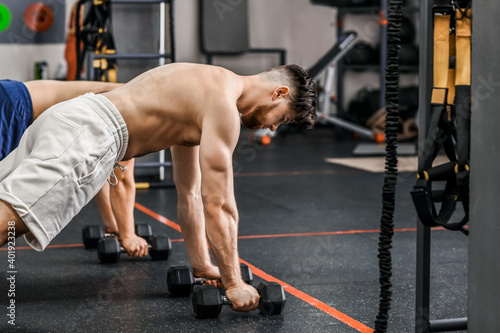 Handsome muscular men exercising with dumbbells in gym